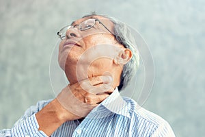 Portrait of senior man touching his neck and having throat irritation photo