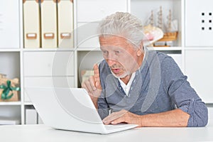 Portrait of a senior man using laptop at home