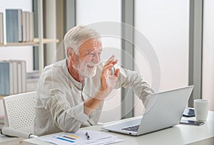 Portrait of senior man using laptop using laptop talking on video call at home, Happy senior man in living room with laptop