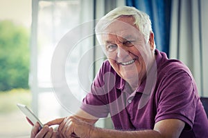 Portrait of senior man using mobile phone at home