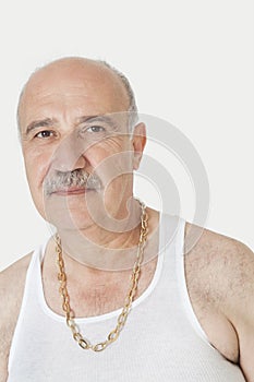 Portrait of senior man in vest with gold chain over gray background