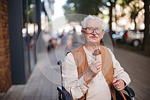 Portrait of senior man on wheelchair, eating ice cream on a hot summer day.