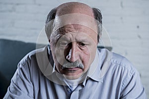 Portrait of senior mature old man on his 60s at home couch alone feeling sad and worried suffering pain and depression