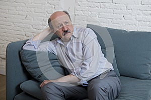 Portrait of senior mature old man on his 60s at home couch alone feeling sad and worried suffering pain and depression