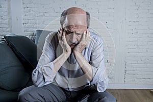 Portrait of senior mature old man on his 60s at home couch alone feeling sad and worried suffering pain and depression