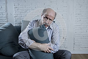 Portrait of senior mature old man on his 60s at home couch alone feeling sad and worried suffering pain and depression