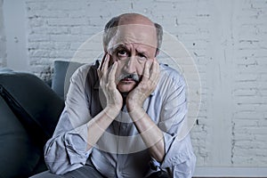 Portrait of senior mature old man on his 60s at home couch alone feeling sad and worried suffering pain and depression