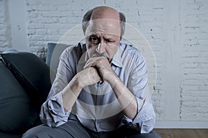 Portrait of senior mature old man on his 60s at home couch alone feeling sad and worried suffering pain and depression