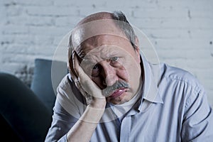 Portrait of senior mature old man on his 60s at home couch alone feeling sad and worried suffering pain and depression