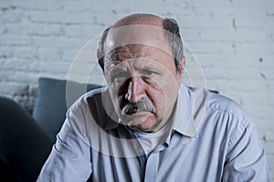 Portrait of senior mature old man on his 60s at home couch alone feeling sad and worried suffering pain and depression