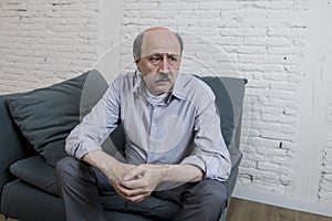 Portrait of senior mature old man on his 60s at home couch alone feeling sad and worried suffering pain and depression