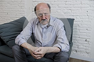 Portrait of senior mature old man on his 60s at home couch alone feeling sad and worried suffering pain and depression