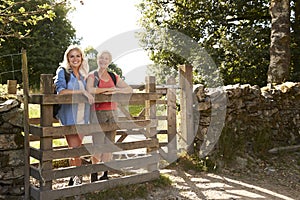 Portrait Of Senior Mother With Adult Daughter Hiking In Lake District UK Looking Over Wooden Gate