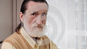 Portrait of a senior old man with gray beard turn head looking at the camera.