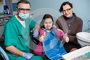 Portrait of senior pediatric dentist and girl with her mother on the first dental visit at the dental office