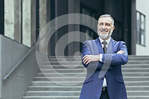 Portrait of senior real estate agent man. He stands next to a business suit near a modern building