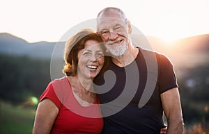 Portrait of senior tourist couple hikers standing in nature, looking at camera.