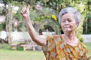 Portrait of a senior woman with arms raised while standing in a garden. Concept of aged people and healthcare