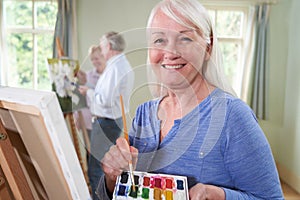 Portrait Of Senior Woman Attending Painting Class With Teacher          In Background