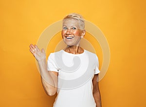 Portrait of senior woman with cute smile over yellow background