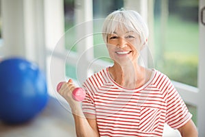 Portrait of senior woman exercising with dumbbell at home