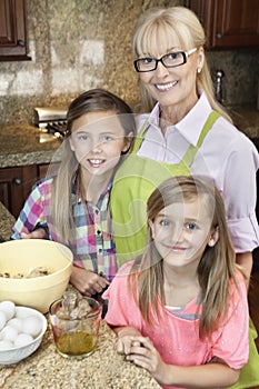 Portrait of a senior woman with granddaughters in kitchen