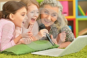 Portrait of senior woman with granddaughters using laptop