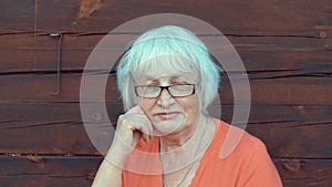 Portrait senior woman with gray hair looking in camera on wooden wall background