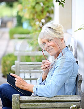 Portrait of senior woman outdoors reading book
