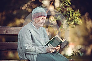 Portrait of senior woman in park reading book