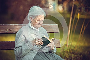 Portrait of senior woman in park reading book