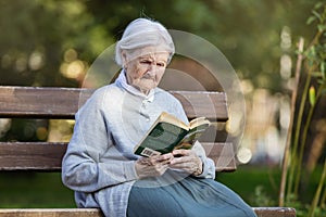 Portrait of senior woman in park reading fiction book