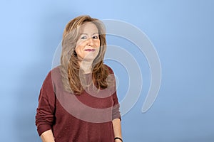 Portrait of senior woman with positive attitude and smiling on blue studio background.