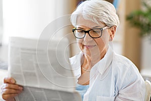 Portrait of senior woman reading newspaper at home