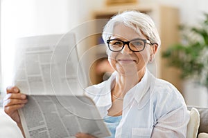 Portrait of senior woman reading newspaper at home