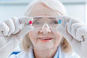 Portrait of senior woman scientist showing pills in hands