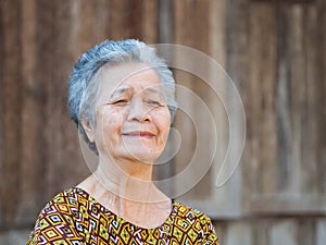 Portrait of a senior woman with short gray hair, smiling and looking away while standing outdoors.