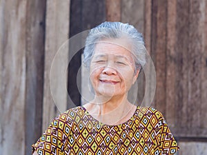 Portrait of a senior woman with short gray hair, smiling and looking at the camera while standing outdoors.