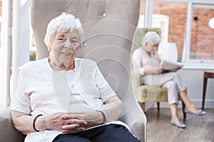 Portrait Of Senior Woman Sitting In Chair In Lounge Of Retirement Home