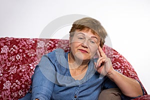 Portrait of a senior woman sitting at home in a comfortable chair. Thoughtful look