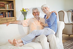 Portrait of senior woman sitting on mans lap in living room