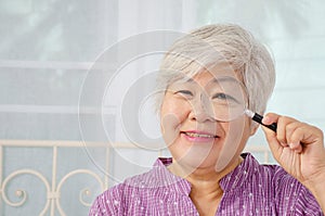 Portrait of a senior woman smile looking through magnifying glass, enlarged eye
