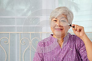 Portrait of a senior woman smile looking through magnifying glass, enlarged eye