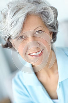 Portrait of a senior woman smiling with great teeth. Happy attractive old female alone at her home. Beautiful elderly