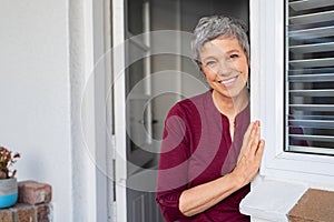 Happy senior woman leaning at door