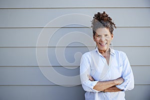 Portrait Of Senior Woman Standing Outside Grey Clapboard House