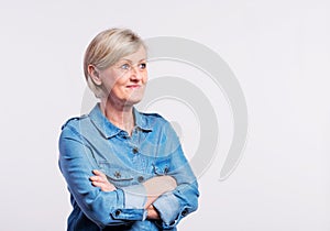 Portrait of a senior woman in studio, arms crossed.