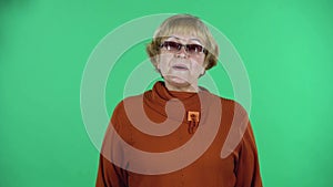 Portrait of senior woman takes off her medical disposable mask and takes a deep breat, isolated over green background.