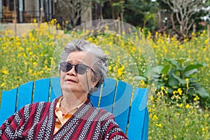 Portrait of a senior woman wearing sunglasses while sitting side the lake. Space for text. Concept of aged people and relaxatio photo