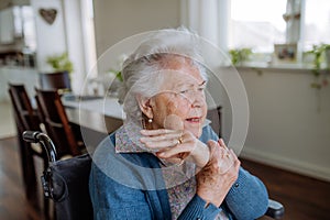 Portrait of senior woman on wheelchair with pain in her hand.